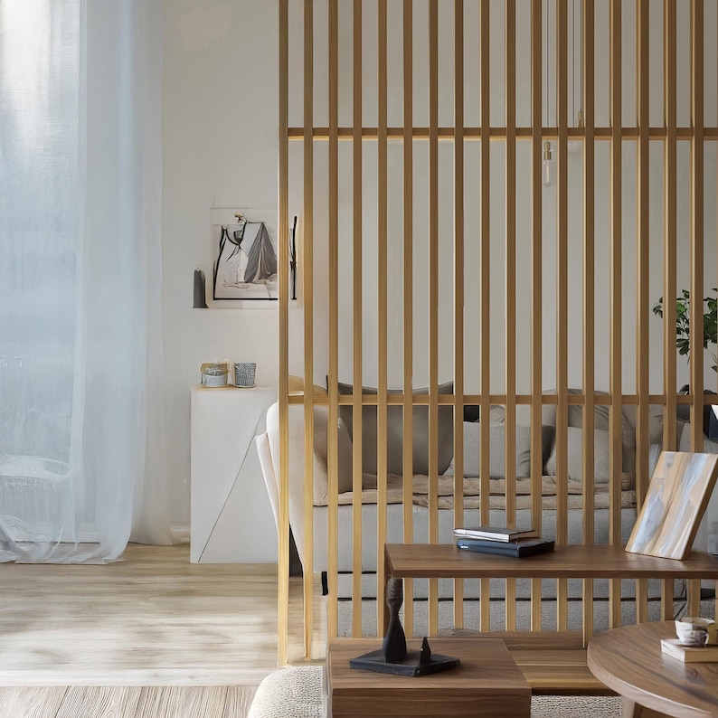 Contemporary living space with a wooden slatted partition, neutral-toned furniture, and soft natural lighting