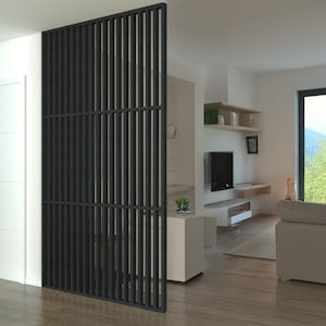 Modern living space with a black slatted partition, white walls, a cozy seating area, and large windows overlooking a scenic outdoor view.