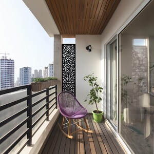 Modern balcony with a purple rocking chair, potted plant, wooden ceiling, and a decorative privacy screen overlooking a city skyline.