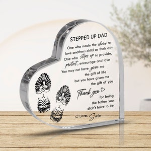 May include: A clear heart-shaped crystal paperweight with a message about a Stepped Up Dad. The message reads: "One who made the choice to love another's child as their own. One who steps up to provide, protect, encourage and love. You may not have given me the gift of life but you have given me the gift of you. Thank you for being the father you didn't have to be. Love, Sara".