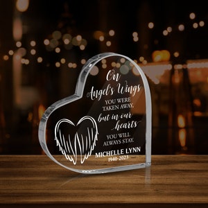 Peut inclure: Un cœur en verre transparent en forme de cœur avec le texte "On Angel's Wings You Were Taken Away, But In Our Hearts You Will Always Stay." Le nom "Michelle Lynn" et les dates "1940-2023" sont également gravés sur le cœur.
