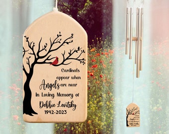 May include: Wooden wind chime with a cardinal and tree design. The chime has the text "Cardinals appear when Angels are near. In loving memory of Debbie Levitsky 1942-2023".