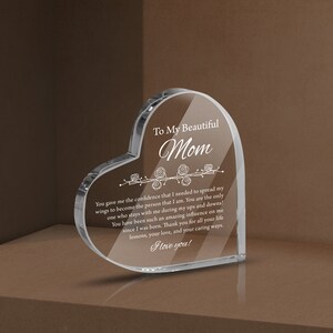 May include: A heart-shaped crystal paperweight with a message engraved on it. The message reads "To My Beautiful Mom You gave me the confidence that I needed to spread my wings to become the person that I am. You are the only one who stays with me during my ups and downs! You have been such an amazing influence on me since I was born. Thank you for all your life lessons, your love, and your caring ways. I love you!"