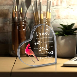 May include: A heart-shaped clear acrylic memorial with a red cardinal illustration. The text reads "My mind still talks to you and my heart still looks for you but my soul knows you're at peace." The name "Jesse Williams 1943-2022" is also included.