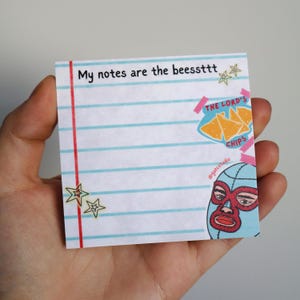 May include: A lined notepad with the text "My notes are the beessttt" and illustrations of stars, tortilla chips, and a luchador mask. The notepad has a red vertical line and blue horizontal lines.