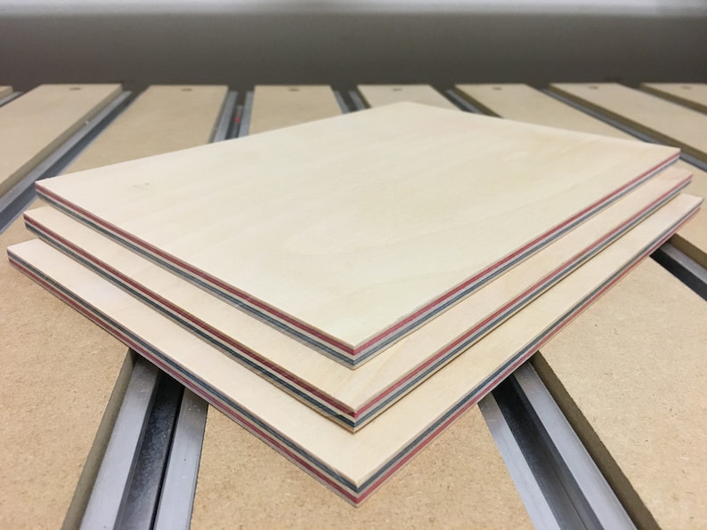 May include: Three pieces of plywood stacked on top of each other. The plywood is light brown with red and black edging.