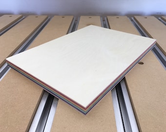 May include: A stack of colorful paper sheets with a white top layer. The paper is arranged in a rainbow pattern.