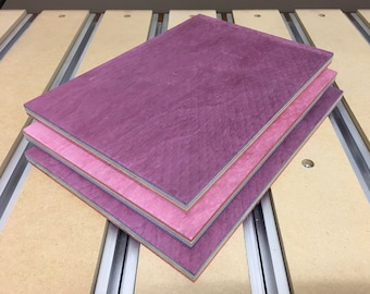 May include: Three pieces of wood veneer stacked on top of each other. The top piece is a deep purple, the middle piece is a light pink, and the bottom piece is a light blue.