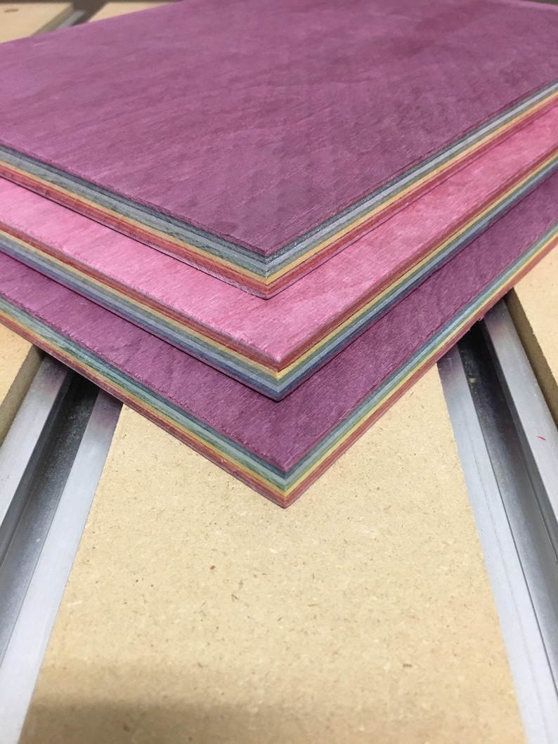 Pode incluir: Uma pilha de finas t&aacute;buas de madeira com um arco-&iacute;ris de cores sobrepostas. As t&aacute;buas s&atilde;o tingidas em tons de roxo, rosa e amarelo.