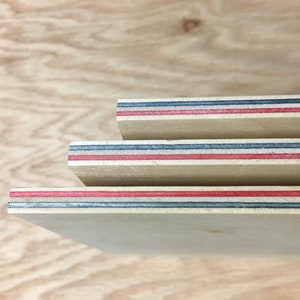May include: Close-up of three pieces of plywood with red, blue, and white stripes along the edges.