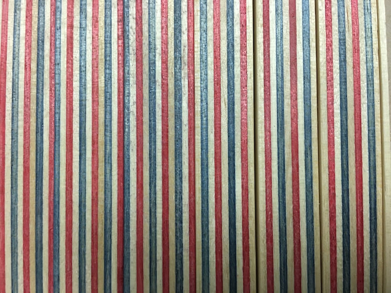 May include: Close-up of a wooden surface with alternating red, blue, and natural wood stripes. The wood is stained and has a slightly distressed look.