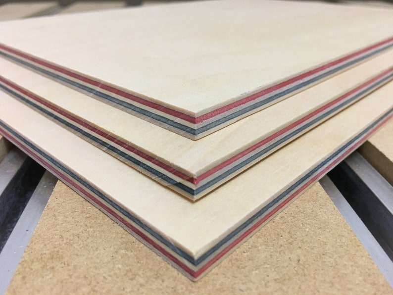 May include: Three pieces of plywood stacked on top of each other. The plywood has a light wood color with red, blue, and black stripes along the edges.