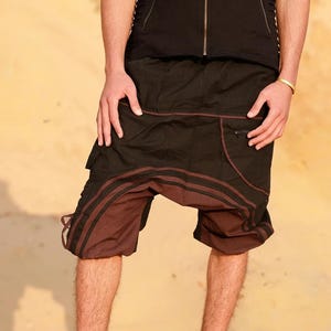 May include: A person wearing brown and black shorts with a black sleeveless vest. The shorts have a brown stripe down the side and a black stripe down the center.
