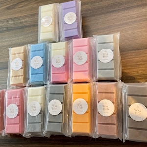 May include: Assortment of 18 wax melts in various colours and scents, packaged individually in clear plastic bags. Each melt features a round label with the text "Wax Hub" printed in black.