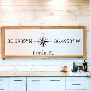 May include: A framed sign with a compass and the coordinates 30.3935° N 86.4958° W and the text "Destin, FL".