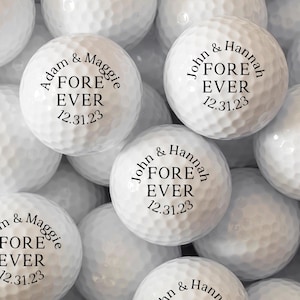 May include: White golf balls with black text that reads "Adam & Maggie FORE EVER 12.31.23" and "John & Hannah FORE EVER 12.31.23".