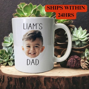 May include: White ceramic mug with a photo of a child's face and the text "Liam's Dad" printed on it.