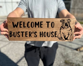 May include: A wooden sign with the text "Welcome to Buster's House" and a black silhouette of a bulldog.