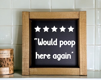 May include: A wooden framed sign with a black chalkboard insert. The chalkboard has five white stars and the text "Would poop here again".