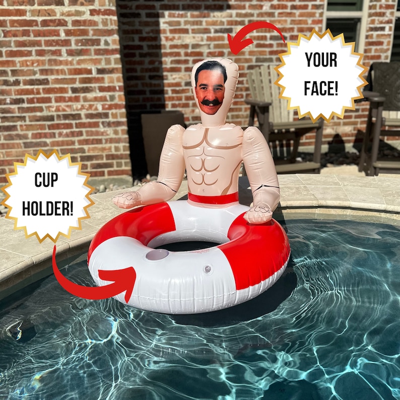 May include: Inflatable pool float shaped like a muscular man with a red and white life preserver. The float has a cutout for a face and the text "YOUR FACE!" is displayed. The text "CUP HOLDER!" is also displayed.