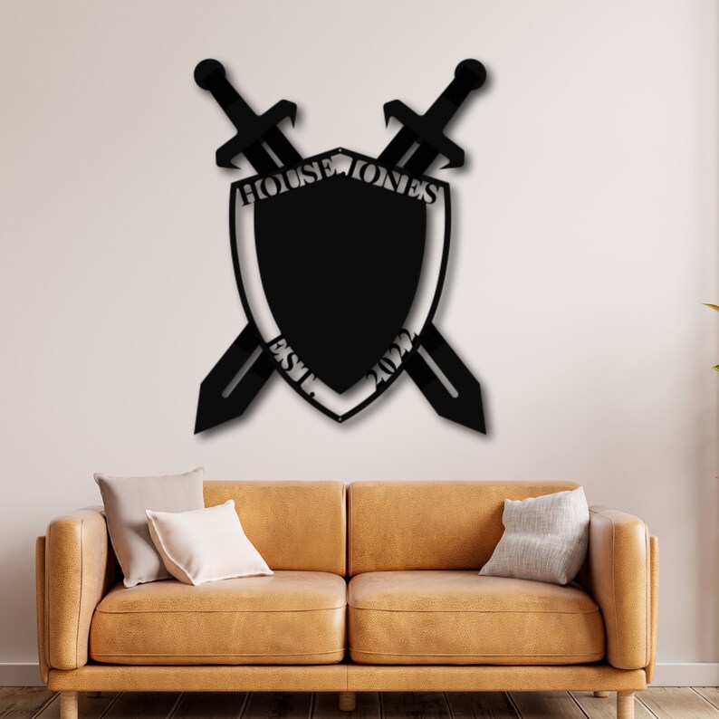 May include: Black metal wall decor featuring a shield with crossed swords. The shield has the text "House Jones Est. 2022" around the perimeter.