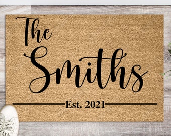 May include: A brown coir doormat with the text "The Smiths Est. 2021" in black cursive lettering.