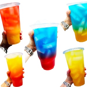 May include: Four clear plastic cups filled with different colored beverages. The cups are filled with red, blue, yellow, and a layered blue and red beverage. Each cup has ice cubes in it.