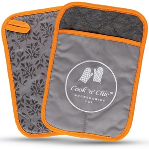 May include: A pair of gray oven mitts with orange trim. The mitts have a quilted texture and a floral pattern on one side. The other side has a white embroidered logo that says "Cook 'n Chic™ Accessories USA".