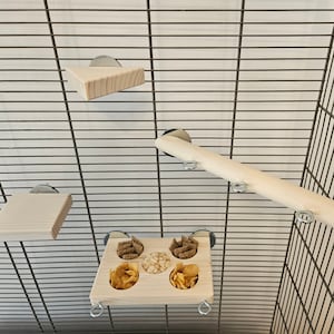 May include: A wooden bird cage with multiple perches and a food dish. The perches are attached to the cage with metal clips. The food dish has six compartments filled with different types of bird food.