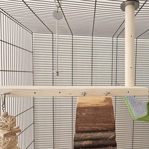 May include: A wooden bird cage accessory set. Includes a wooden perch, a hanging ladder, a wooden and bark platform, a green and gray hammock, and a hanging toy. The cage is made of black metal.