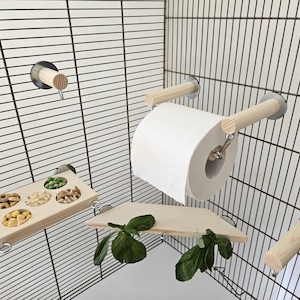 May include: A set of wooden bird toys for a cage, including a hanging food dish, a perch, a swing, and a toilet paper roll holder. The toys are attached to the cage with suction cups.