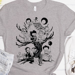 May include: A gray t-shirt with a black and white illustration of horror movie characters in a treehouse. The characters include Freddy Krueger, Jason Voorhees, Michael Myers, Leatherface, and Chucky.