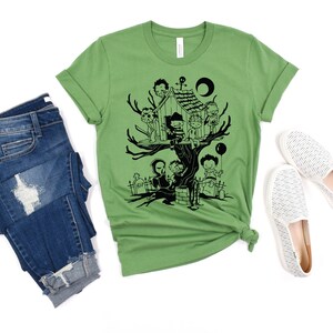 May include: A green t-shirt with a black graphic of horror movie characters in a treehouse. The characters include Freddy Krueger, Jason Voorhees, Michael Myers, and others.