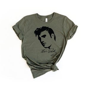 May include: A green t-shirt with a black silhouette of Elvis Presley's face and his signature.