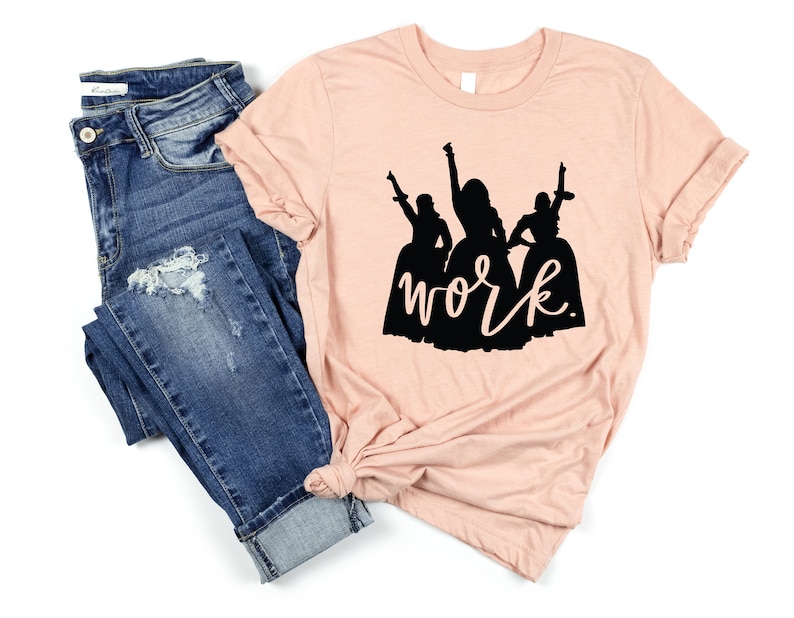 Peut inclure: Un t-shirt couleur p&ecirc;che avec une silhouette noire de trois femmes en robes et le mot "work" &eacute;crit en dessous.