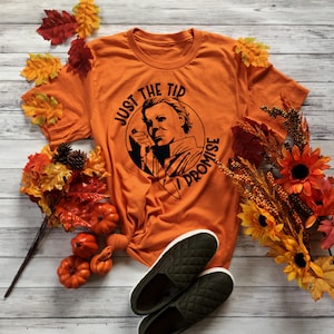 Pu&ograve; includere: Maglietta arancione con una grafica nera di Michael Myers del film Halloween. La grafica dice "Just the tip I promise".