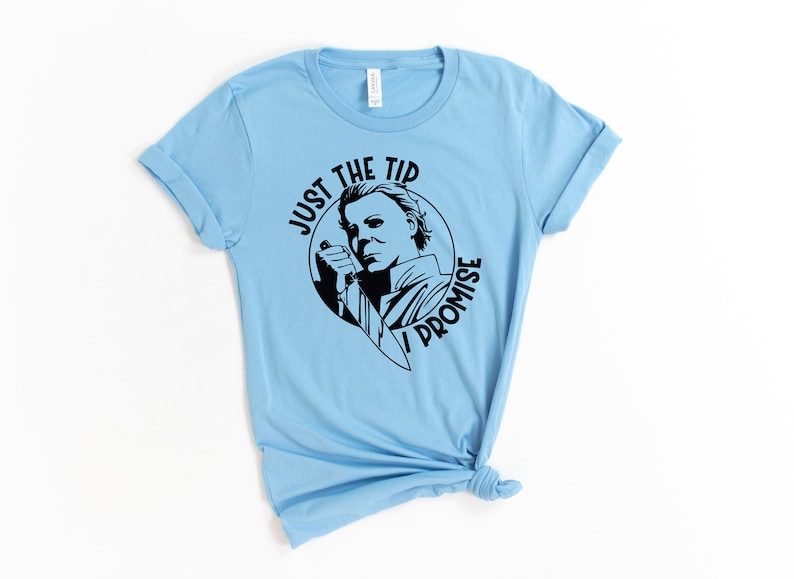 Pu&ograve; includere: Maglietta blu chiaro con una grafica nera di Michael Myers del film Halloween. La grafica dice "Just the tip I promise".