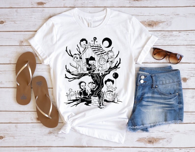 May include: A white t-shirt with a black and white illustration of horror movie characters in a treehouse. The characters include Freddy Krueger, Jason Voorhees, Michael Myers, and Leatherface. The text "RIP" is visible on a tombstone in the illustration.