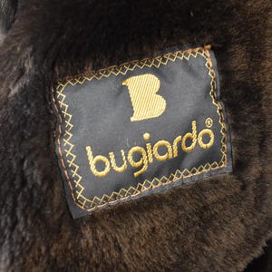 May include: A black fur coat with a brown leather label that says "Bugiarde" with a gold "B" in the upper left corner.