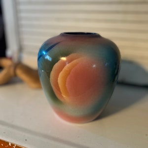 May include: A small, round, blue, green, pink, and orange ceramic vase with a swirl design.