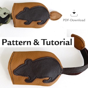Puede incluir: Un llavero de cuero marrón con una correa de cuero marrón y una silueta de ratón de cuero negro. El llavero se vende con un patrón y un tutorial descargables.  PDF-Download
