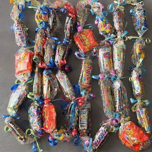 May include: A colorful garland of individually wrapped candy bars, featuring brands like Reese's, Twix, and Hershey's. The candy is wrapped in colorful cellophane and tied together with ribbons.