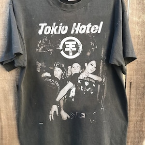 May include: Black t-shirt with a band graphic featuring the band Tokio Hotel. The graphic includes a photo of the band members and the band's logo.