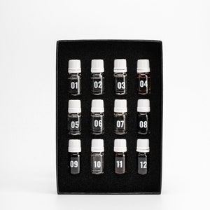 May include: A black box with 12 small glass bottles with white caps. Each bottle is labeled with a number from 01 to 12.