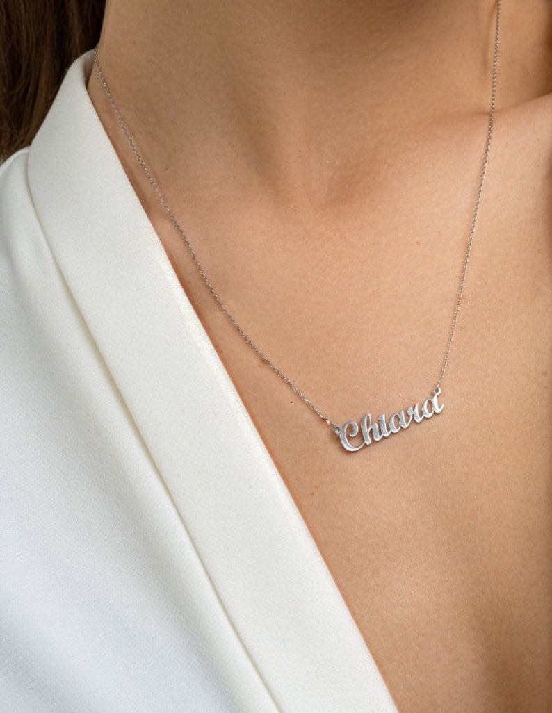 May include: A silver necklace with the name "Chiara" spelled out in cursive script.