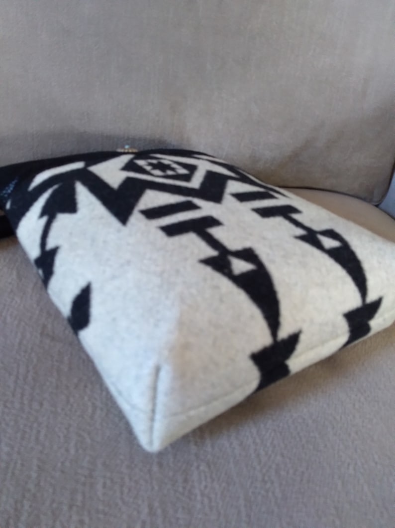 May include: Black and white patterned pillow with a geometric design. The pillow is made of a soft, fuzzy material and has a white border.