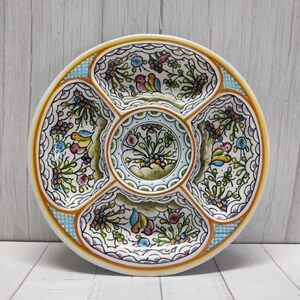 Pode incluir: Um prato de servir de cerâmica branca com cinco seções. Cada seção é decorada com um padrão floral colorido e pássaros pequenos. O prato tem uma borda xadrez azul e branca.
