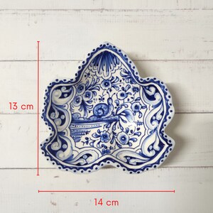 May include: A blue and white ceramic dish with a floral design and a snail. The dish is 13 inches tall and 14 inches wide.