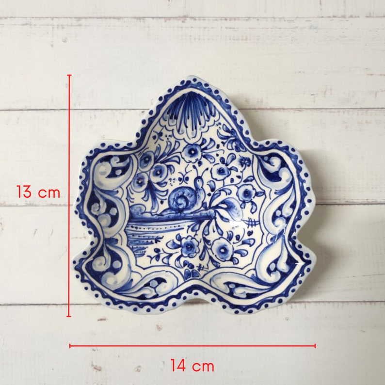 May include: A blue and white ceramic dish with a floral design and a snail. The dish is 13 inches tall and 14 inches wide.