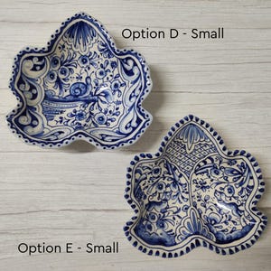 May include: Two small, white ceramic bowls with blue and white floral designs. The bowls are shaped like a leaf and have a scalloped edge. The text "Option D - Small" is above the top bowl and "Option E - Small" is below the bottom bowl.